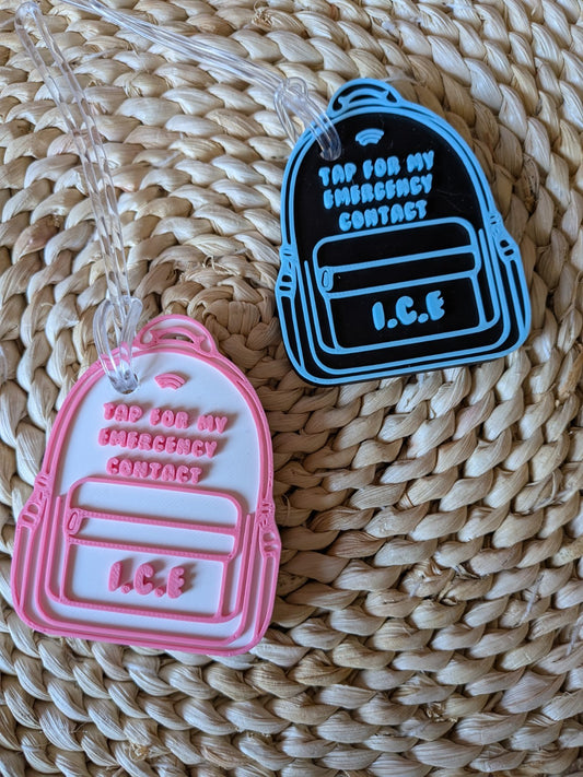 Two 3D-printed emergency contact NFC backpack tags in black and blue and white and pink