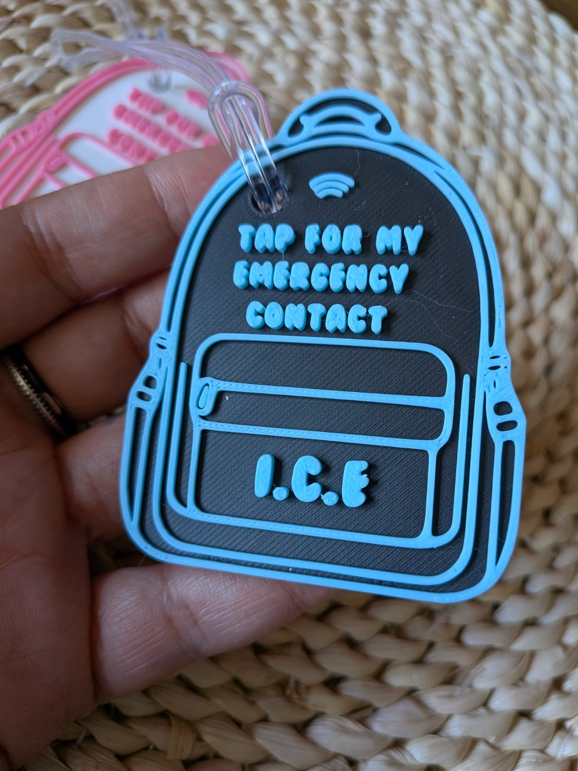 Blue and black 3D-printed emergency contact backpack tag with raised text