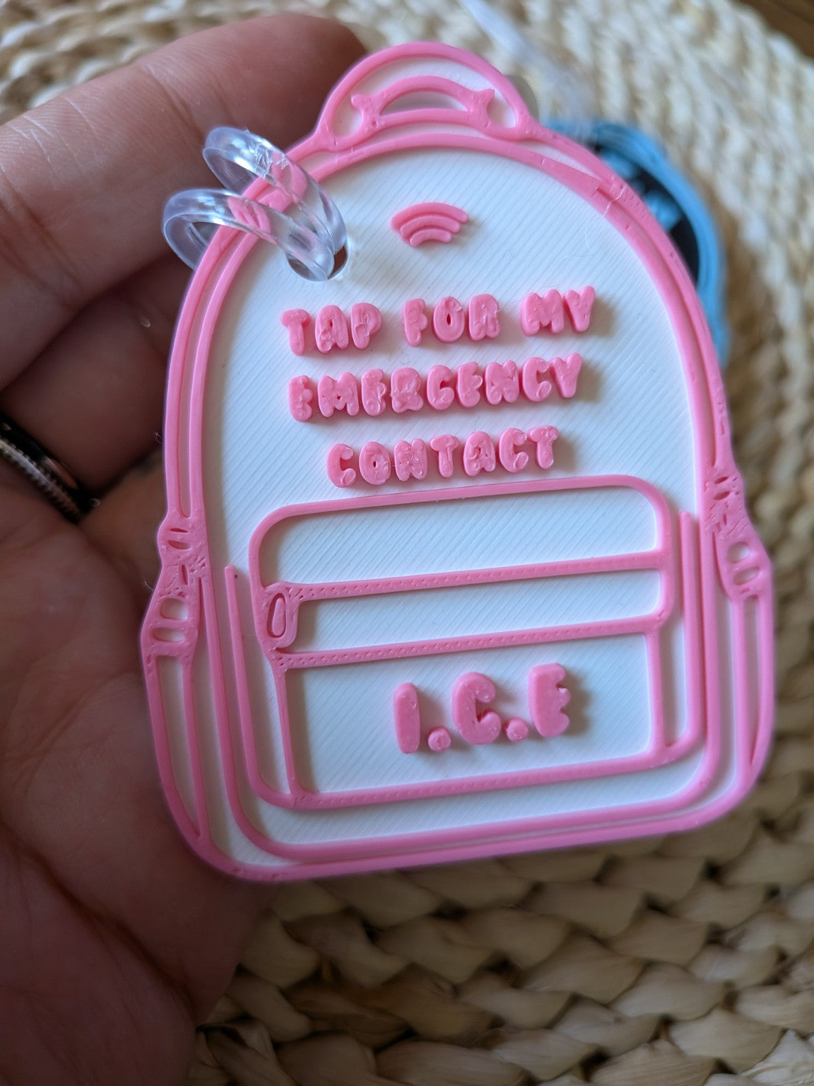 Close-up of pink and white backpack-shaped I.C.E. emergency contact tag