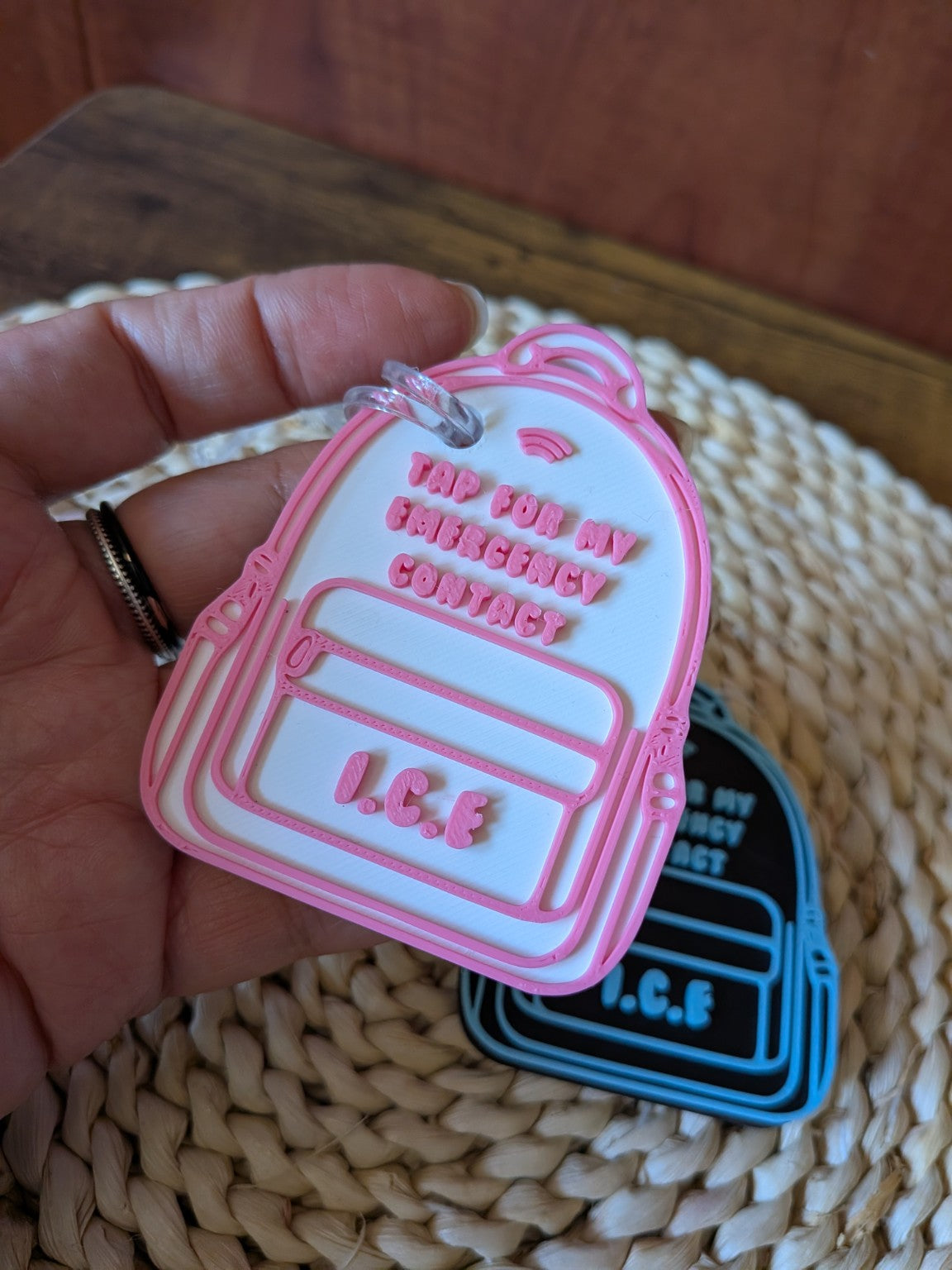 Pink and white 3D-printed NFC I.C.E. backpack bag tag held in a hand