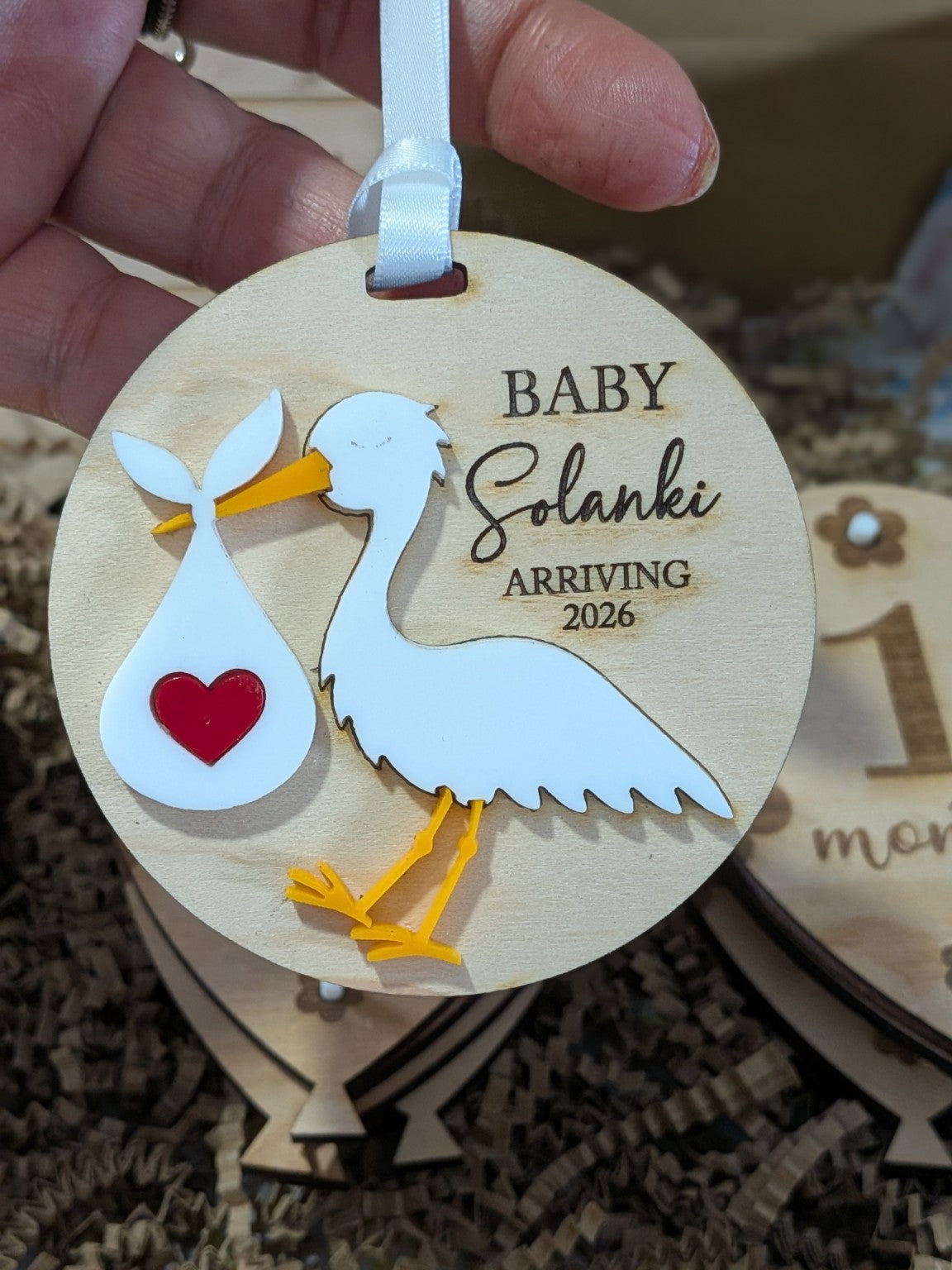 Three-inch round maple plywood baby announcement ornament with layered acrylic stork and personalised engraved name and arrival year