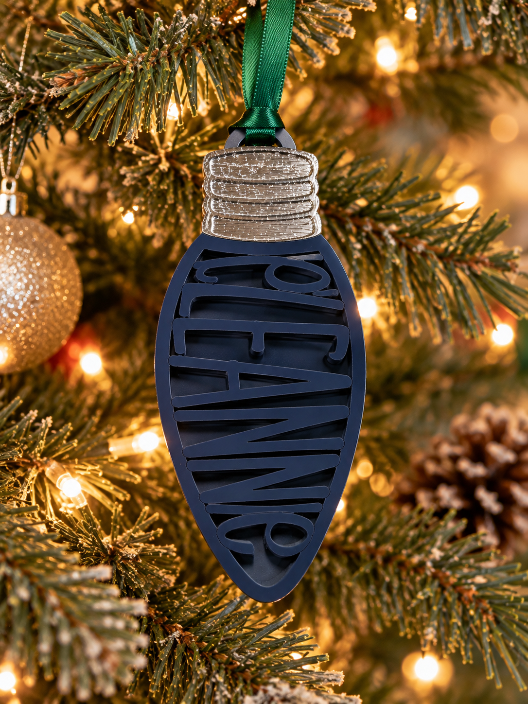 Personalized navy blue Christmas light bulb name ornament hanging on a Christmas tree